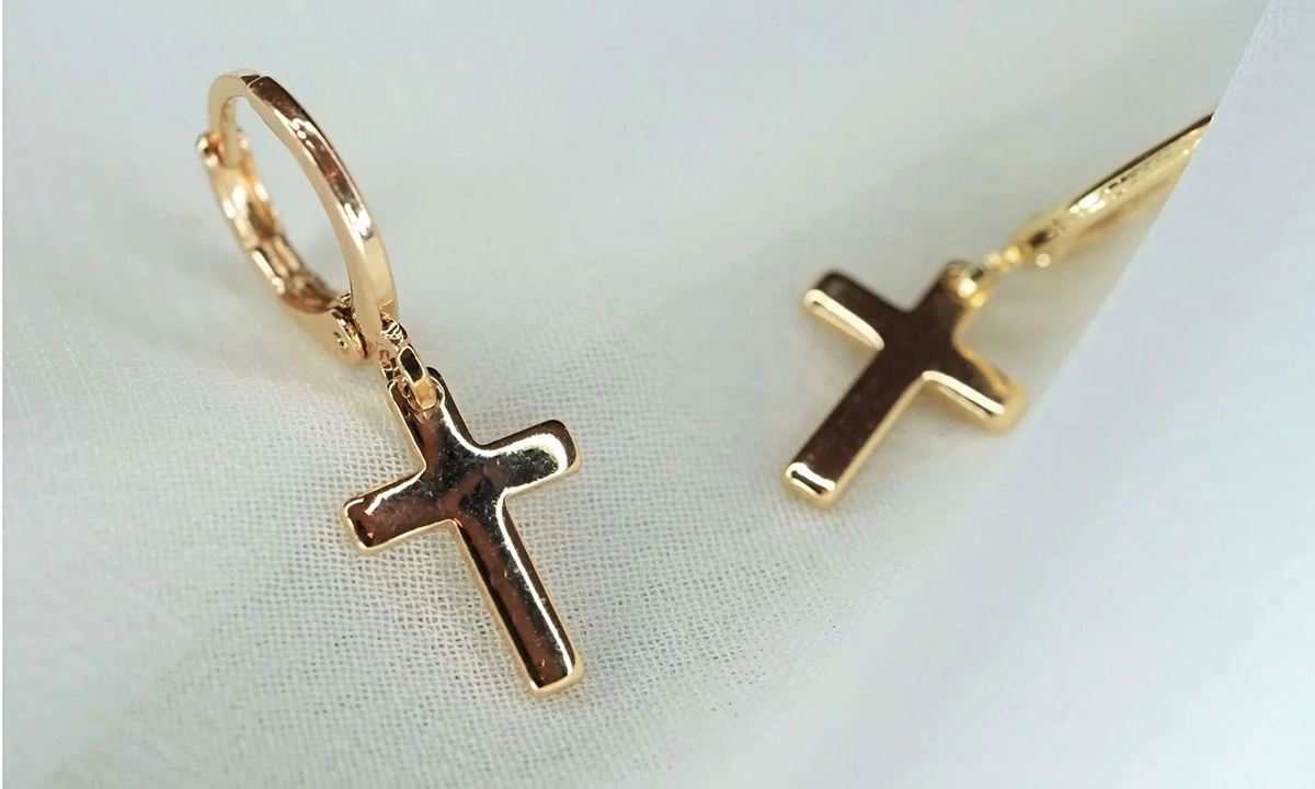 goldene Kreuzohrringe liegen auf einem weißen Tuch