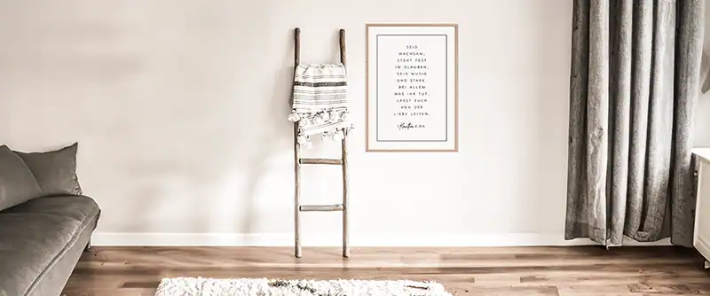 Christliches Poster hängt neben einer an die Wand lehnende Holzleiter in einem Zimmer
