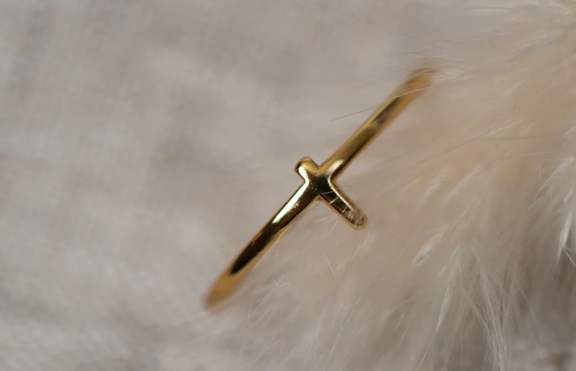 goldener schmaler Ring liegt auf weichen Federn