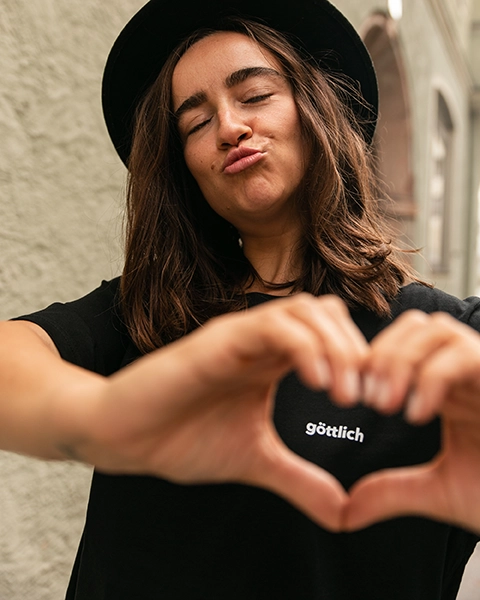 Model trägt schwarzes christliches Shirt und formt mit den Händen ein Herz