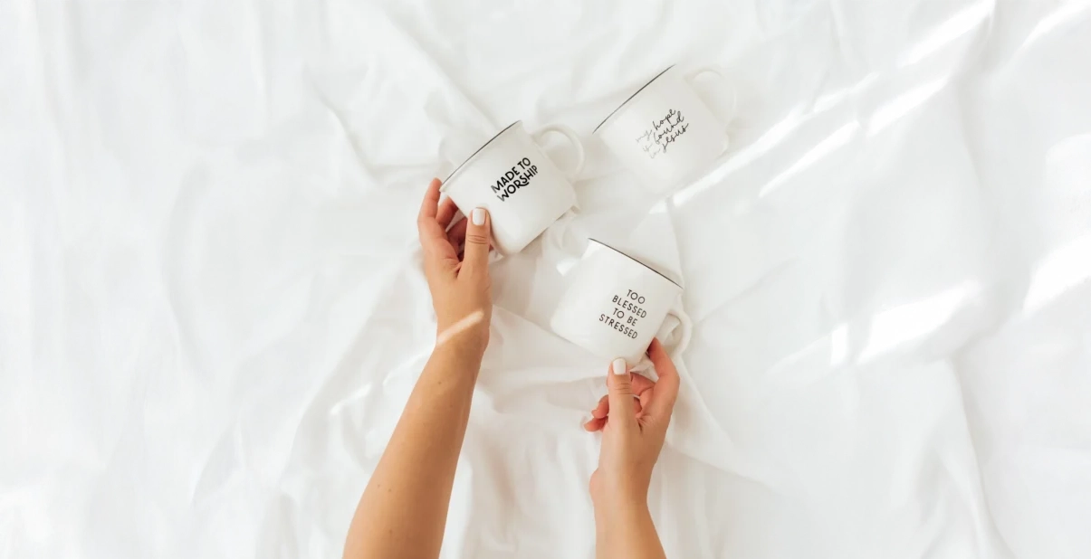 Christliche Tassen werden auf weiße Tischdecke gelegt