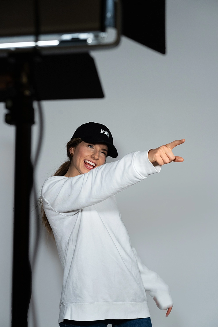 Model steht vor einem Licht und zeigt mit dem Finger zur Seite