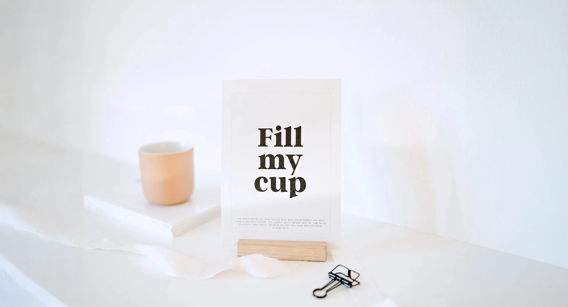 weiße Postkarte mit schwarzer Schrift ‚Fill my cup‘ steht in einem Kartenständer