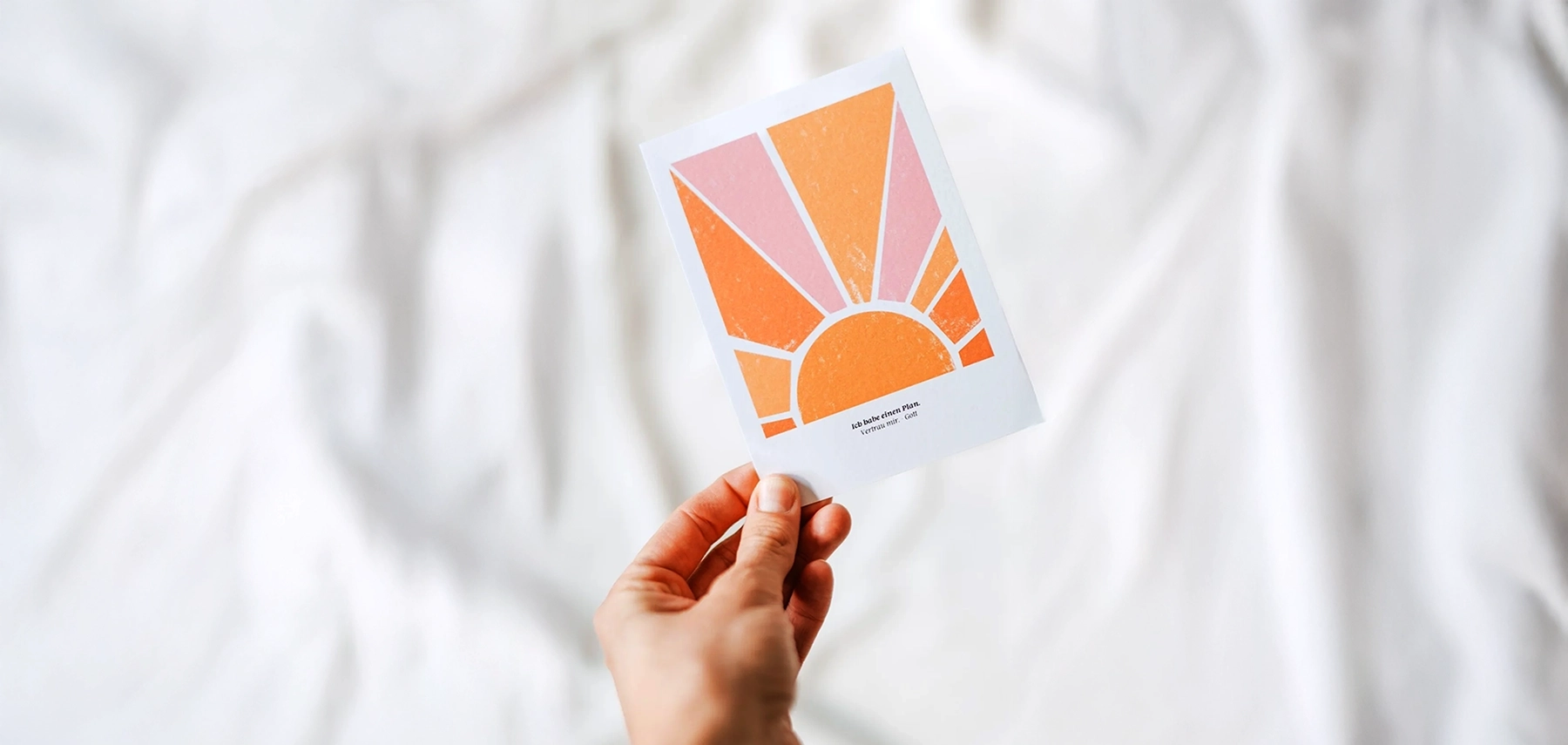 orangene kreative Postkarte wird von einer Hand in die Luft gehalten