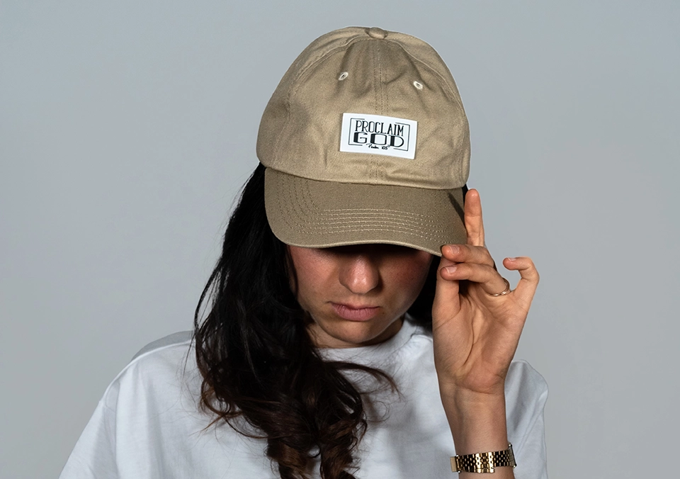 Frau trägt christliche Cap mit Aufschrift und hält sie fest.