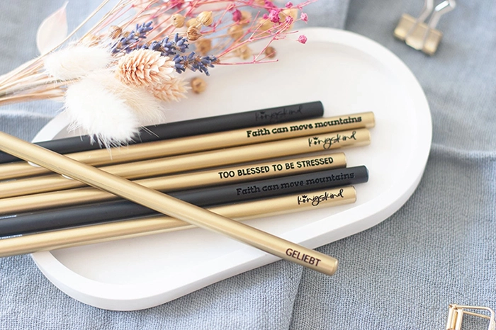 Christliche Stifte in schwarz und gold, liegen in einer weißen Schale