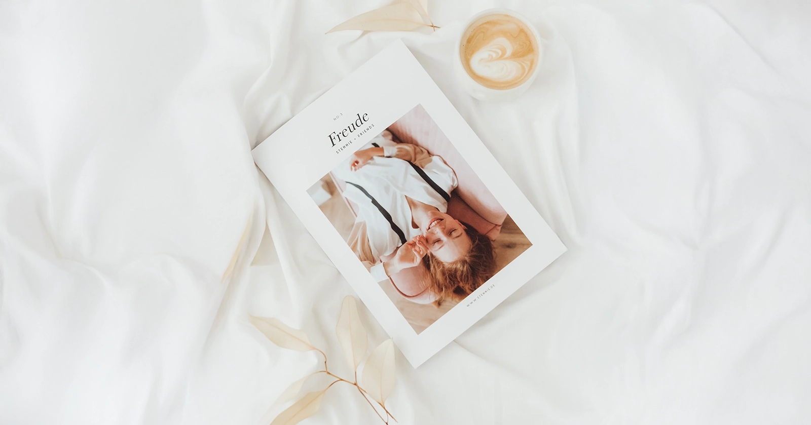 Christliches Magazin „Freude“ liegt auf weißem Tuch neben einem Cappuccino