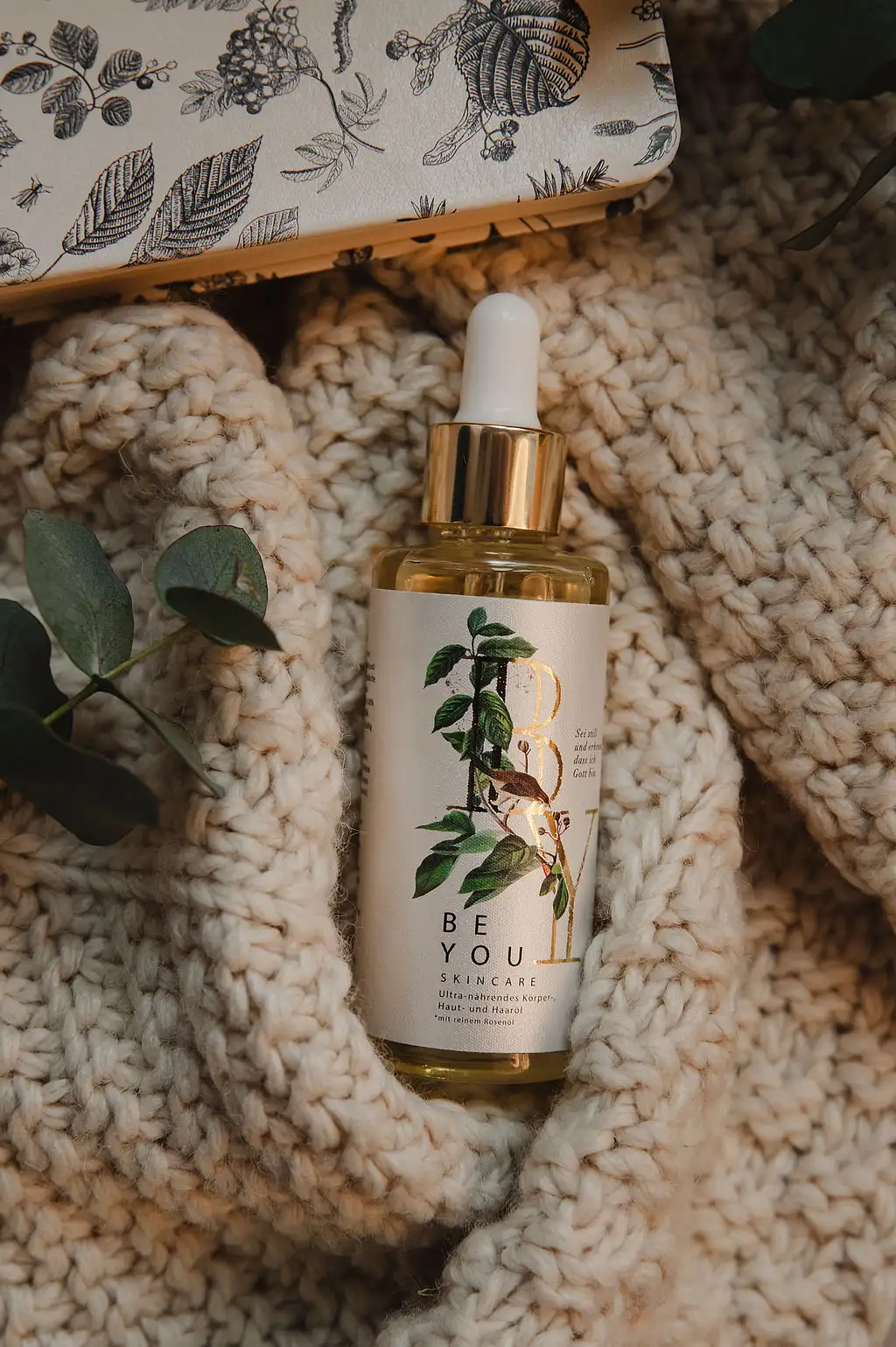 Ultra-nährendes Körper-, Haut- und Haaröl 5 Hautpflege-Serum mit natürlichen Inhaltsstoffen in einer Glasflasche mit Tropfenzähler, umgeben von.