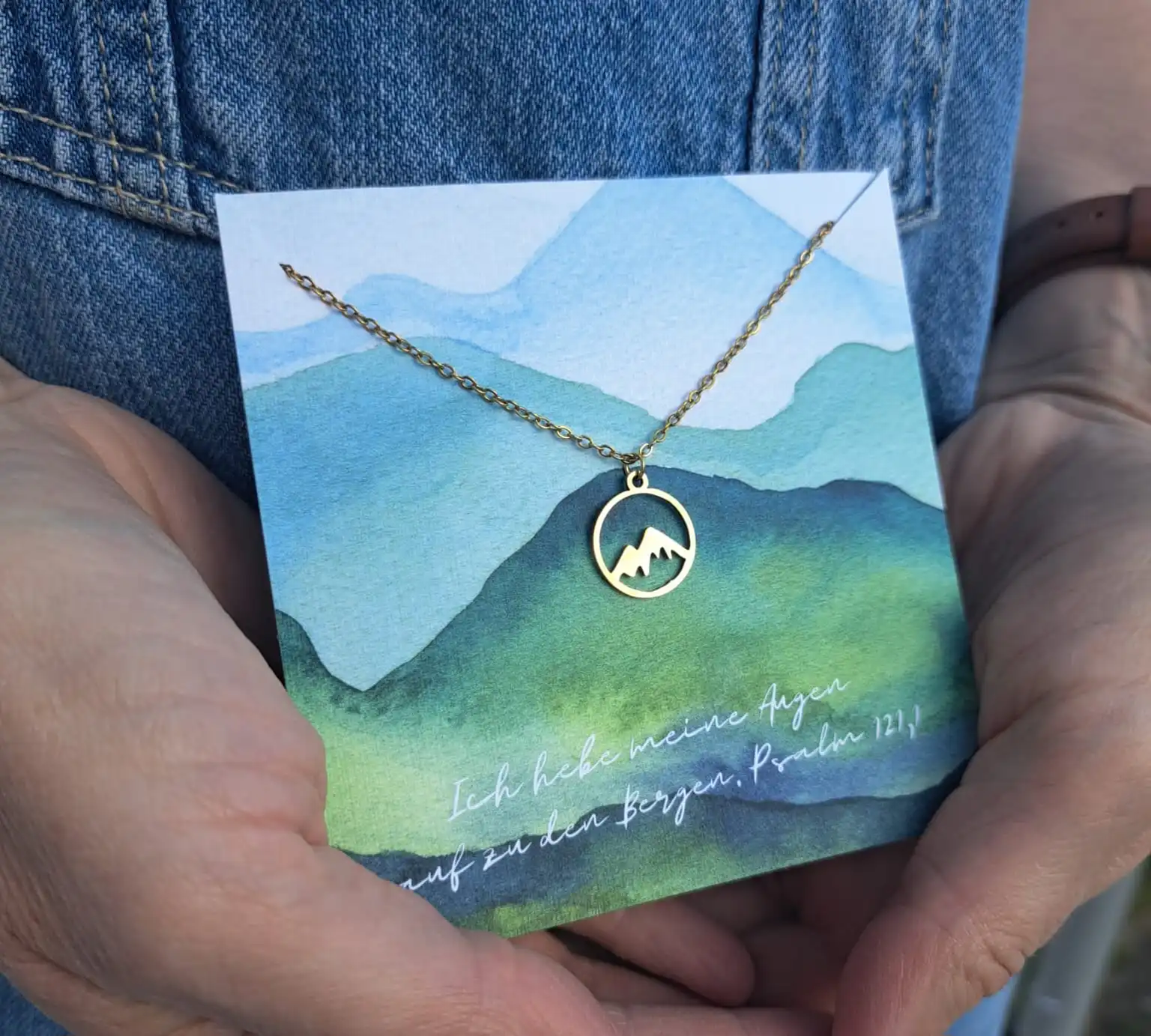 Halskette mit Berg- und Sonnenmotiv auf einer handgemalten Grußkarte, christliche Symbolik.
