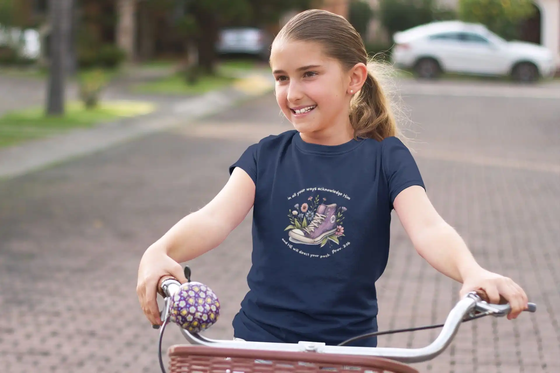 Glaubensstarke Mädchen fährt Fahrrad mit christlichem Design auf T-Shirt.
