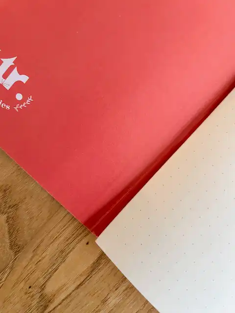 Notizheft "alles neu" 5 Ein offenes Notizbuch mit rotem und weißem Papier auf Holztisch, christliche Marken, Inspiration.