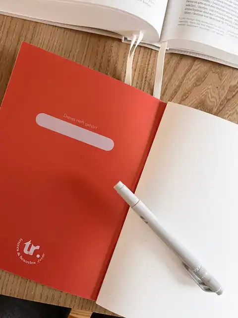 Notizheft "alles neu" 4 Der rote Notizblock mit weißen Texten und Stift auf Holzschreibtisch, christliche Inspiration.
