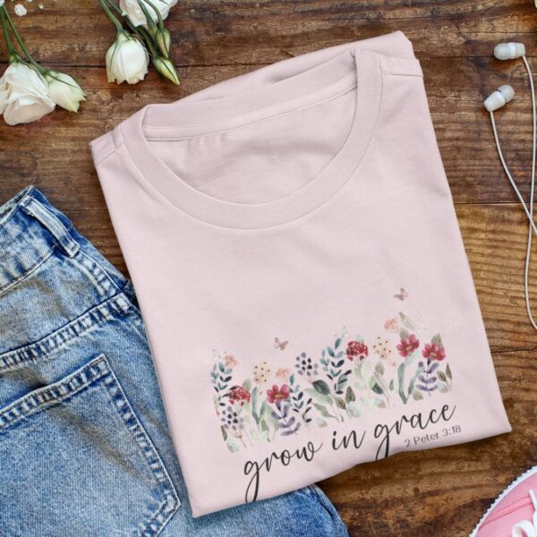 Blumenmuster-T-Shirt mit Bibelvers "grow in grace" auf Holzoberfläche, christliche Mode.