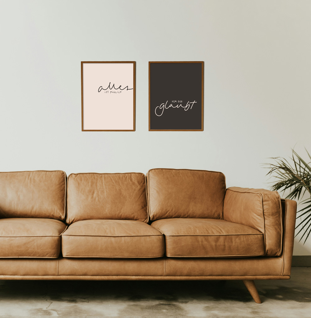 POSTER-DUO "ALLES IST MÖGLICH" 2 Ein gemütliches Wohnzimmer mit braunem Ledersofa und christlichen Wandbildern.