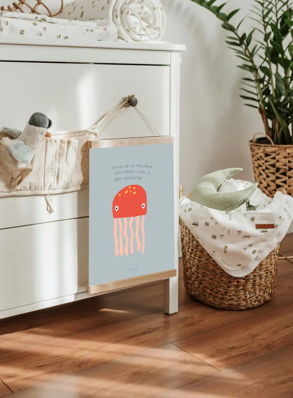 Ein niedliches Kinderzimmer mit einem weißen Kommode, einem Korb mit Babydecken und einem Wandbild m.