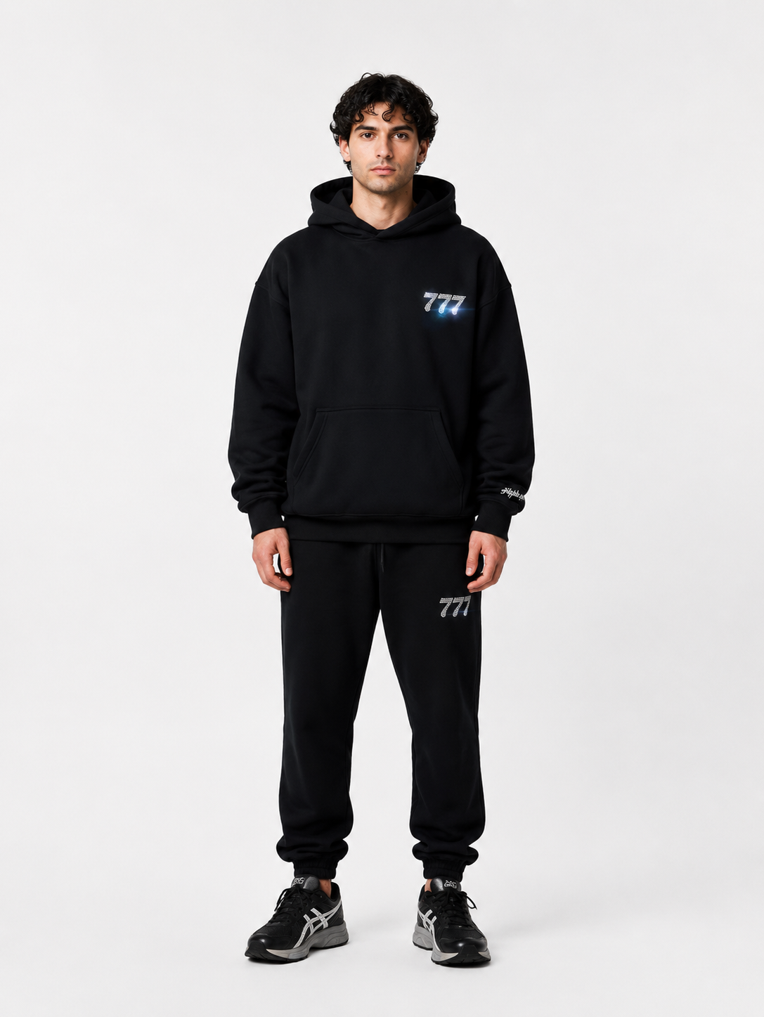 Männer in schwarzem Hoodie und Jogginghose mit "777" Logo, sportlich, casual, modern.