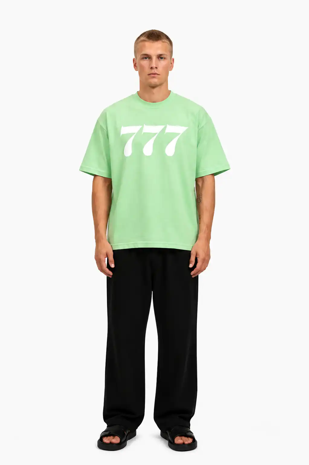 Ein junger Mann trägt ein grünes T-Shirt mit weißen "777" aufdruck, lässig und modern.
