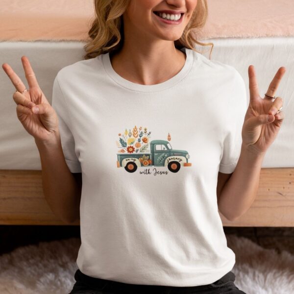 Ein lächelnder Frau trägt ein weißes T-Shirt mit einem bunten, floralen Truck-Design und dem Text "w.