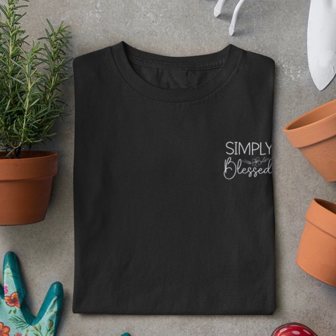 Simply blessed - edles T-Shirt Bio-Baumwolle 2 Ein schwarzes T-Shirt mit dem Text "Simply Blessed" auf einem grauen Hintergrund, umgeben von Pflanz.