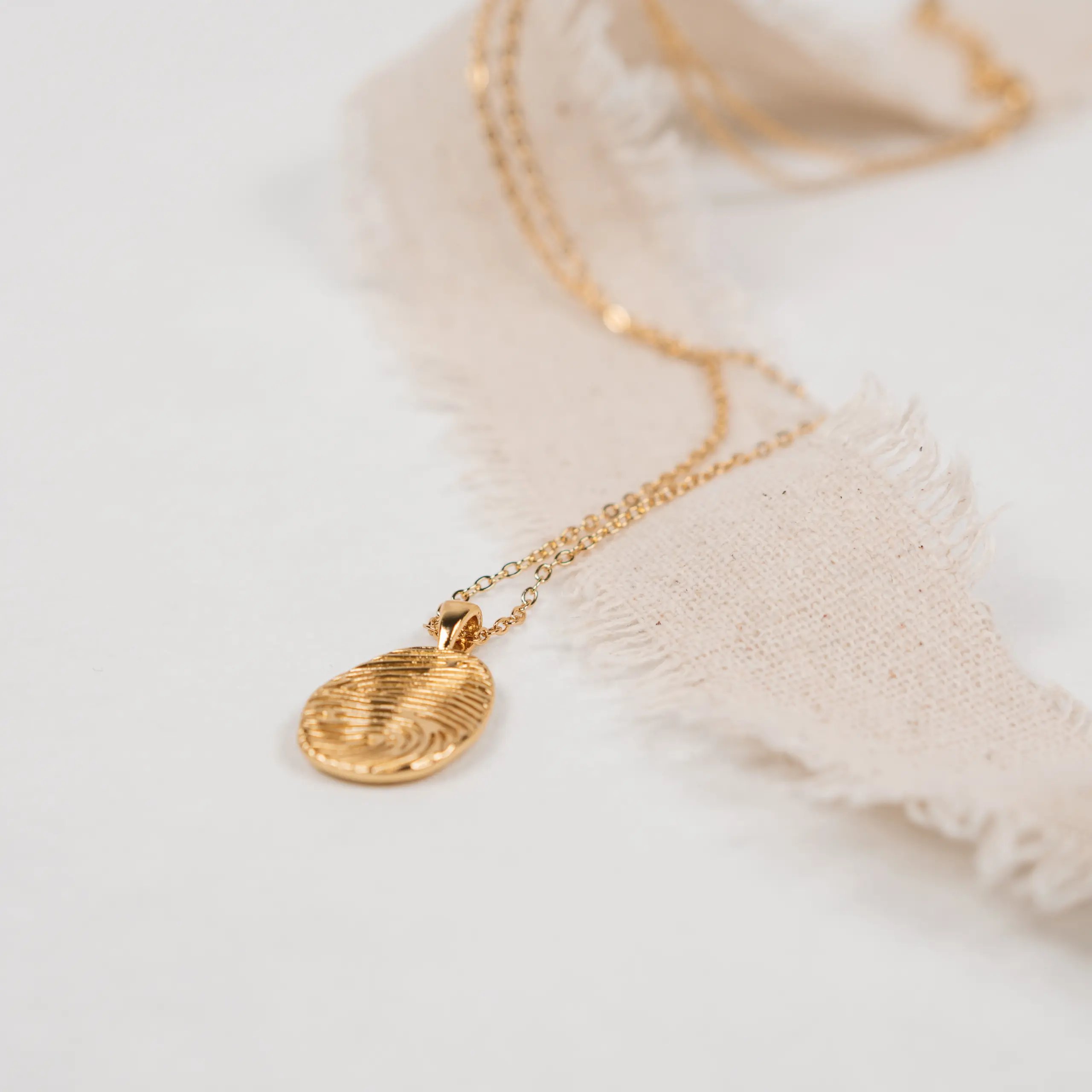 "In Christus" - Halskette | Identität in Christus | vergoldet 2 Goldene Halskette mit Medaillon auf weißem Stoff.