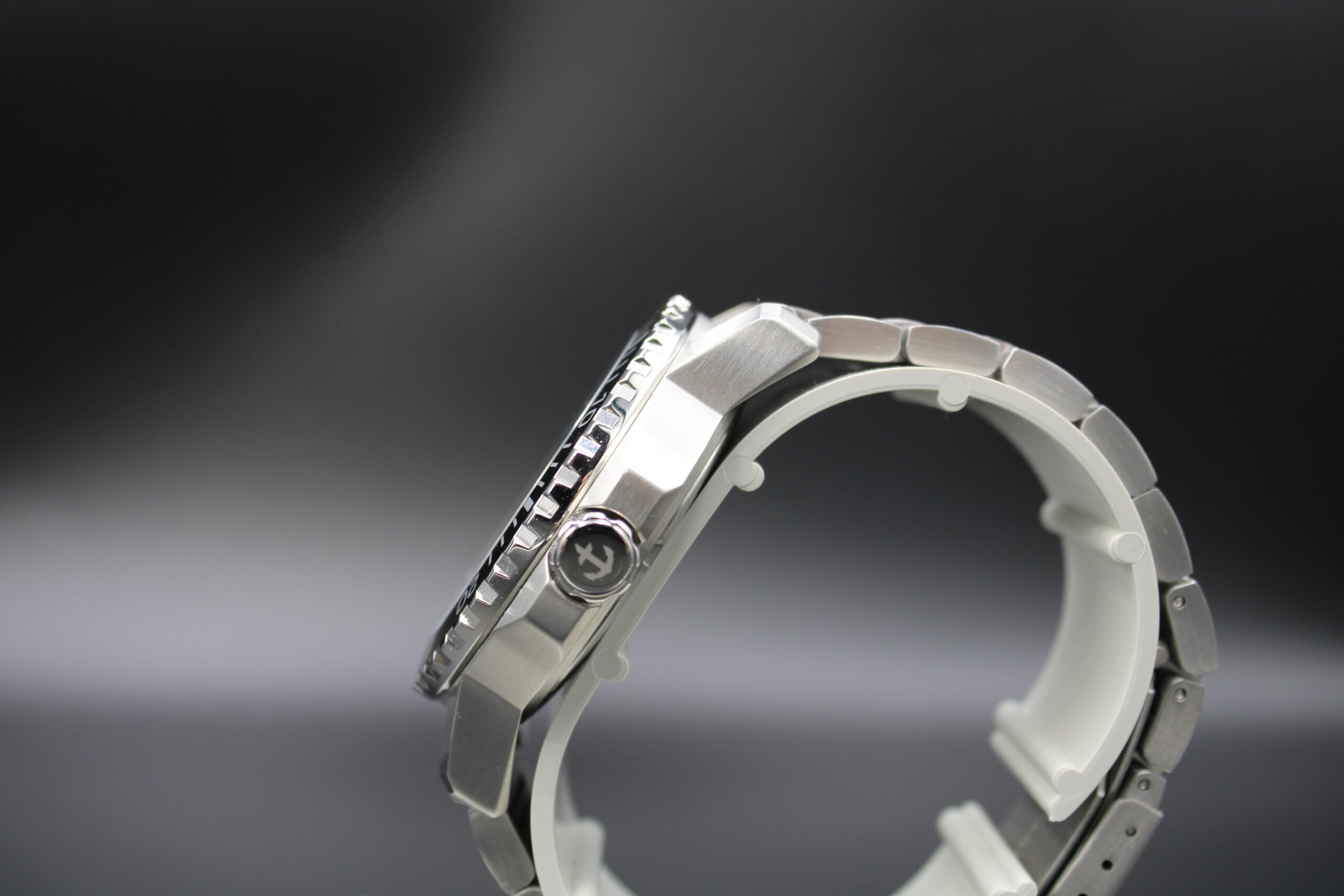 OCEAN OF FAITH - Schweizer Uhr inspiriert vom Glauben - Schwarz Edelstahl 3 Nahaufnahme einer silbernen Armbanduhr mit schwarzem Zifferblatt auf dunklem Hintergrund.