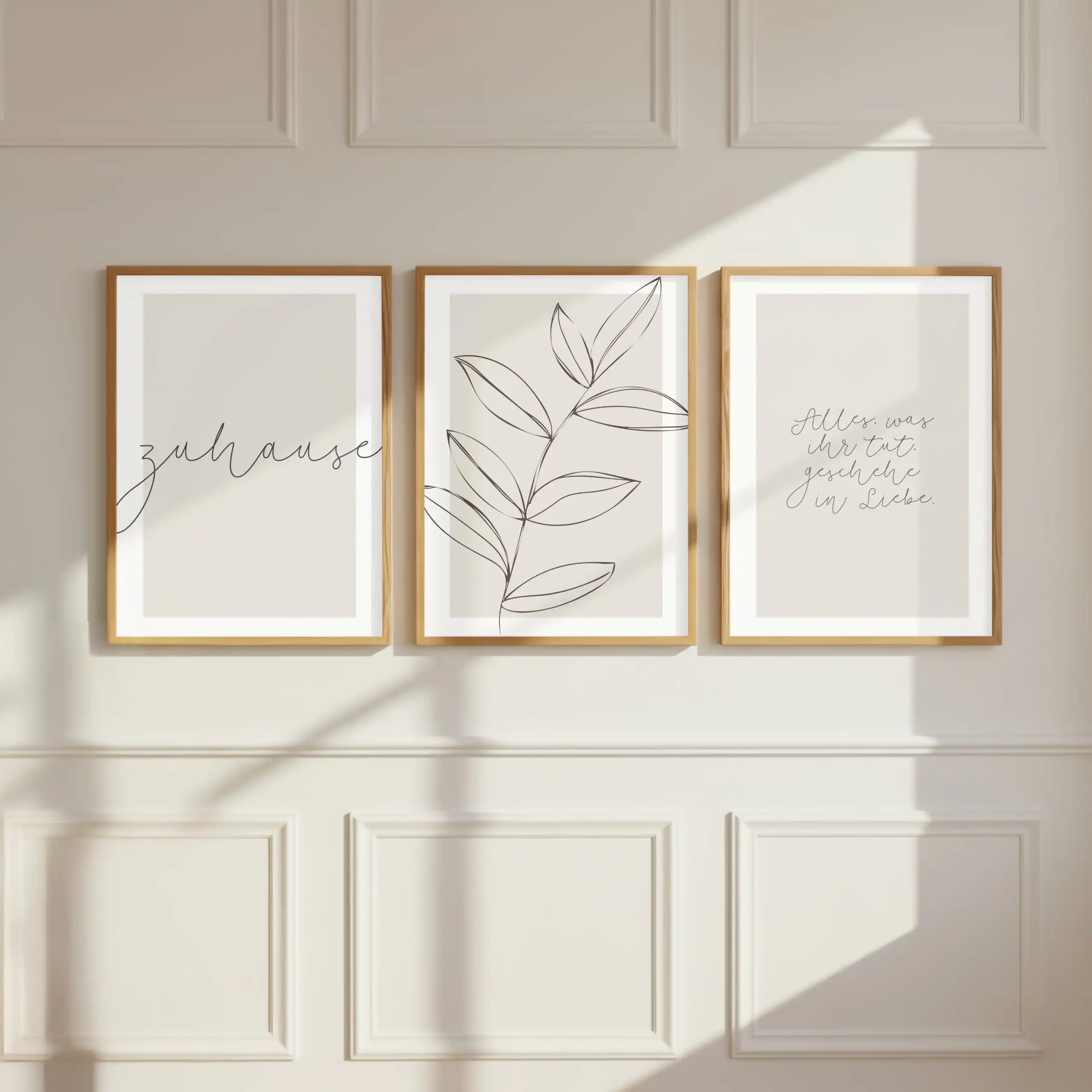 ZUHAUSE - Poster 3er Set in beige 2 Drei minimalistische Bilder mit christlichen Zitaten und Blättern an weißer Wand.