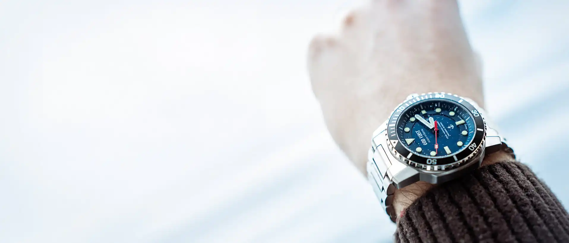 Nahaufnahme eines Handgelenks mit christlicher Uhr und braunem Pullover.