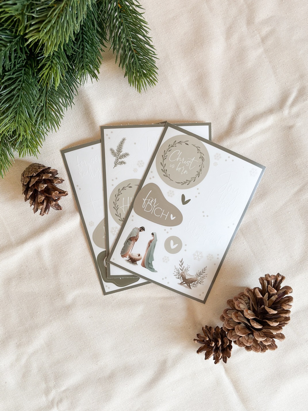 Christliche Grußkarten mit Weihnachtsmotiven und Naturdekor auf Stoff.