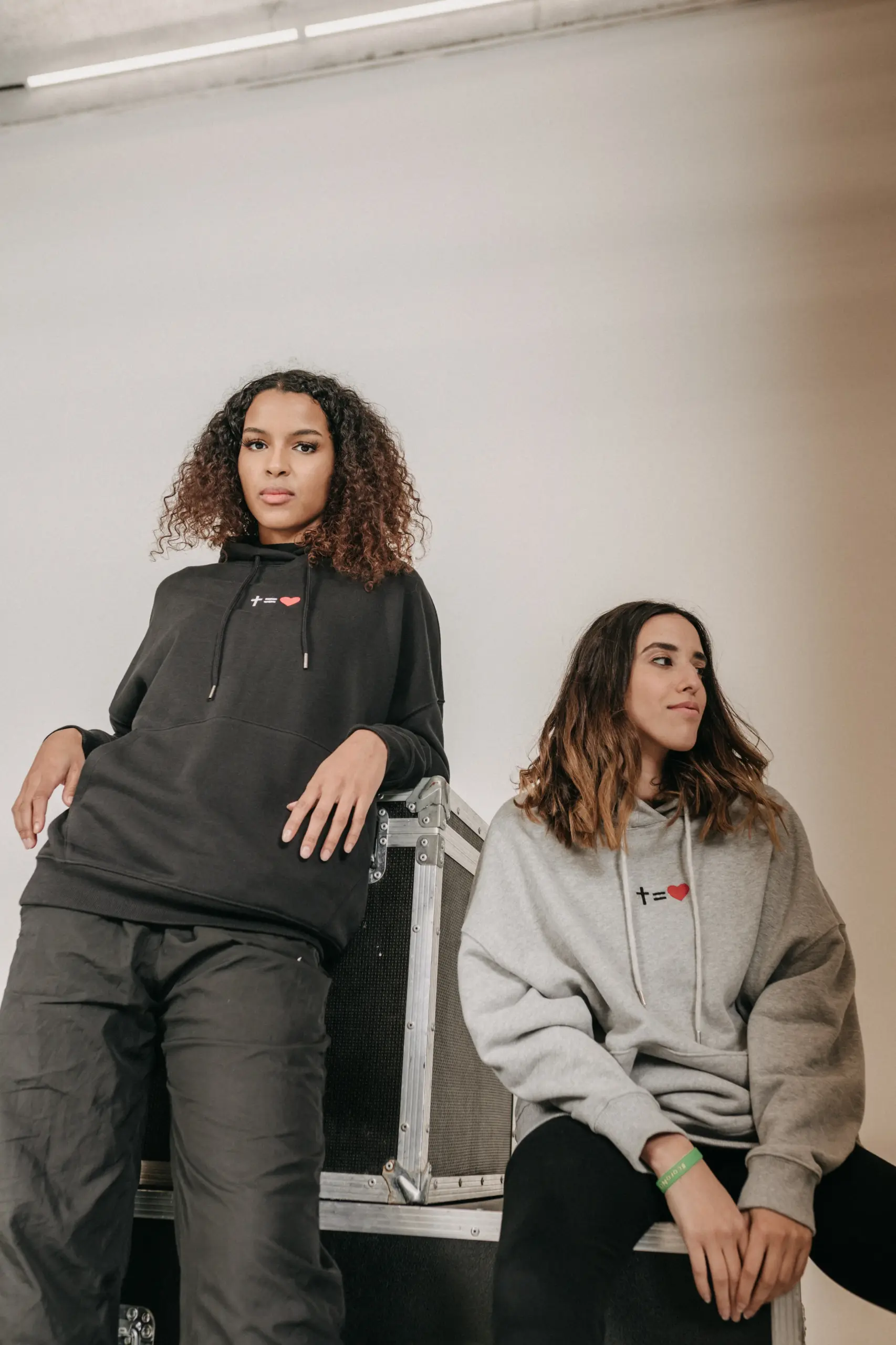 Zwei junge Frauen tragen christliche Hoodies auf einer Bühne bei mookho.de.